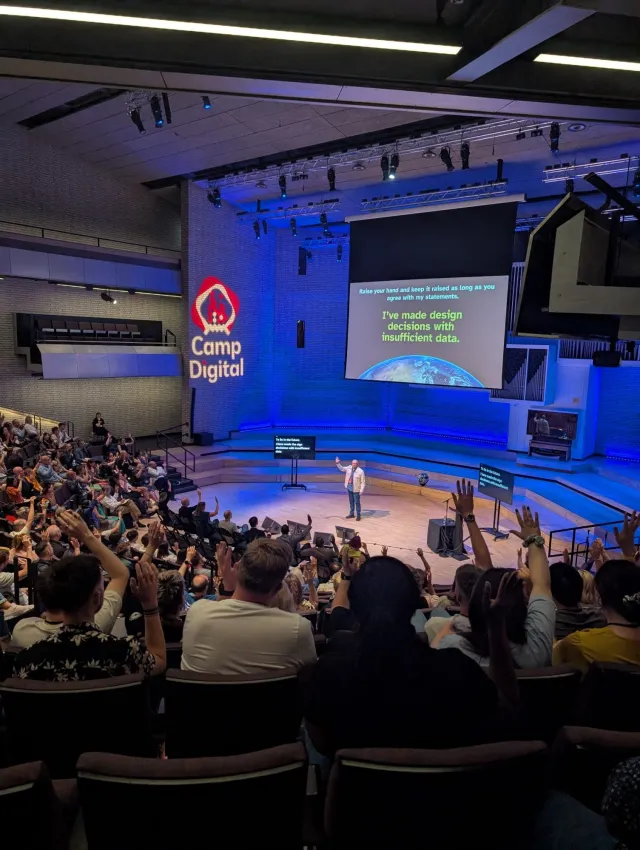 Photo: Becky Colley: Per Axbom on stage at Camp Digital 2025. The audience raising their hands at the slide “I’ve made design decisions with insufficient data.”