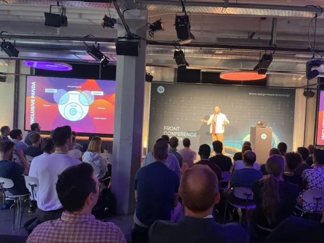 Photo: Roland Sailer: Per Axbom on stage at Front Conference 2022, seen from the audience. The Inclusive Panda diagram is on the big screen.