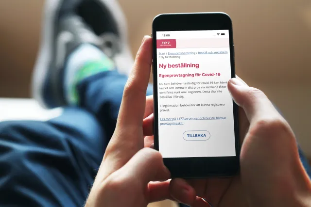 Ordering a test on a phone: A person relaxing on a sofa, ordering a self-test on their phone.