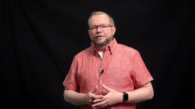 Per Axbom in a red short-sleeved shirt, talking to the camera against a black background.